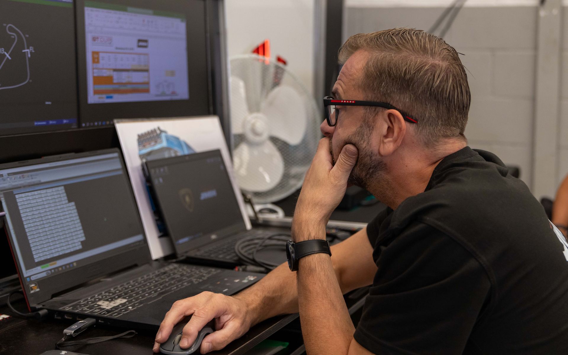 A team engineer studying lap data and setup sheets in the garage
