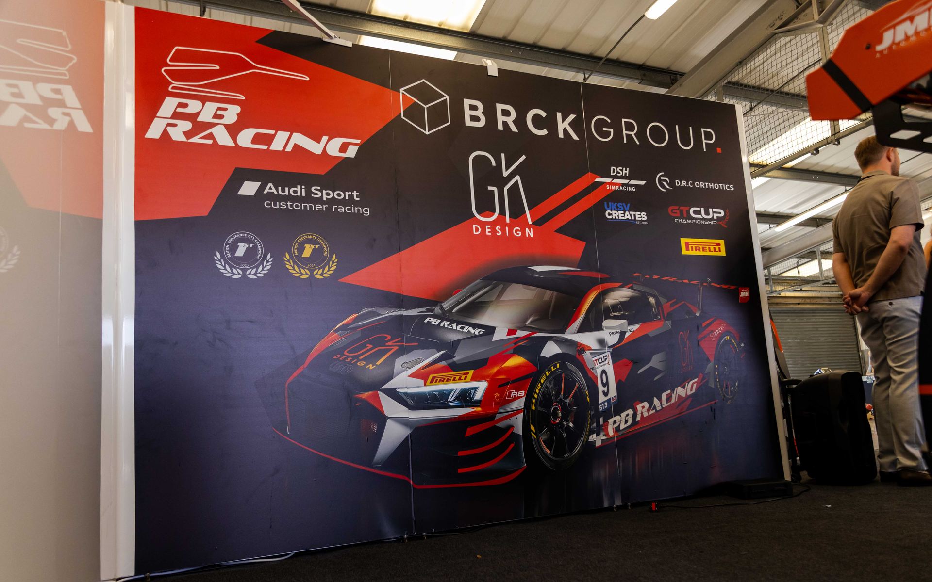 The PB Racing and BRCK Group sponsor board in the paddock