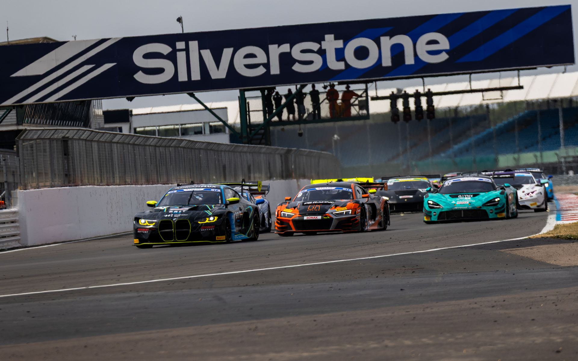 Cars racing under the Silverstone start-finish gantry